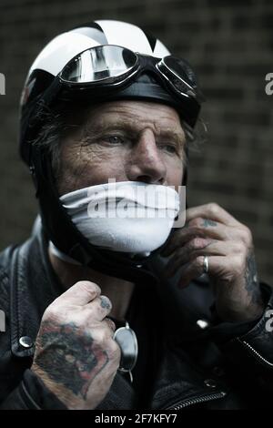 Biker, Cafe Racer mit Schal Mund Abdeckung Motorradhelm und Brille immer bereit. Biker Befestigung Helm. Stockfoto