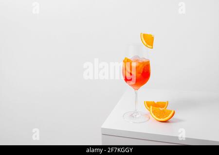 Aperol Spritz Cocktail in Weinglas mit Eis und Orangenscheibe auf weißem Hintergrund. Langes kohlensäurehaltiges Getränk. Minimales kreatives Konzept.
