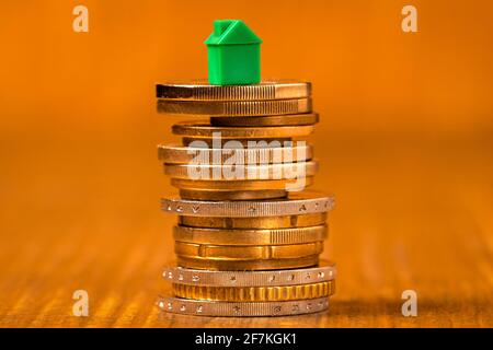 Kleines grünes Haus, das auf Münzstapeln steht. Immobilienkonzept. Stockfoto