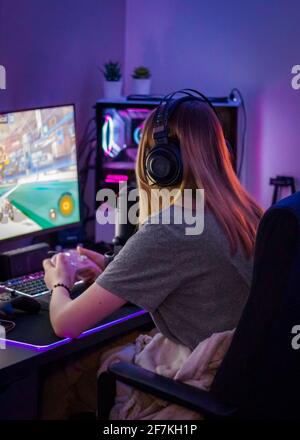 Teenager Mädchen Computer Gamer und Streamer mit Headset an Während der Wiedergabe mit dem Handregler auf den Bildschirm fokussiert Stockfoto