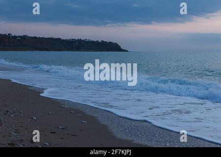 Meer Sand Abend. Blaue Stunde nach Sonnenuntergang an der Küste. Die letzten Sonnenstrahlen spiegeln sich in den Wellen. Am Strand Rollen warme Meereswellen. Die CO Stockfoto