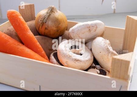 Auswahl von Gemüse in einer kleinen Holzkiste auf einem Küchenabteil Stockfoto