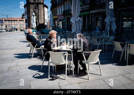 Porto, Portugal. April 2021. Zwei Frauen mit Gesichtsmast werden auf einer Esplanade sitzen gesehen. Die zweite Phase des Definationsprozesses in Portugal begann am 5. April. Restaurants und Cafés durften Menschen auf den Tischen im Freien in Gruppen von 4 Personen pro Tisch beherbergen und die Menschen können nun mit mehr Freiheit durch die Stadt gehen. Kredit: SOPA Images Limited/Alamy Live Nachrichten Stockfoto