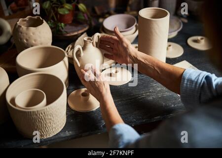 Keramikkünstlerin sitzt am Tisch mit Keramik in Workshop Stockfoto