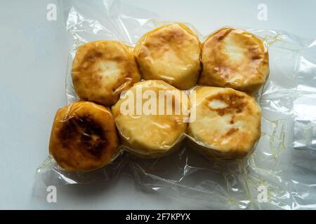 Quark-Pfannkuchen, Syrniki, Pfannkuchen mit Ricotta in Form eines gefrorenen Halbprodukts in einem Vakuumpaket. Pfannkuchen Im Handumdrehen Stockfoto