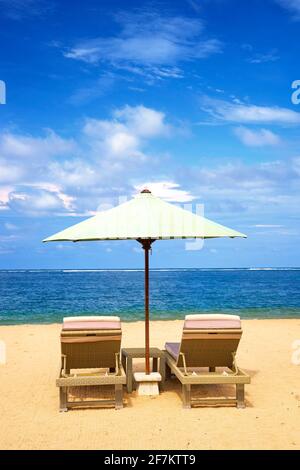 Liegestühle mit Sonnenschirm am Strand von Sanur, Bali, Indonesien Stockfoto