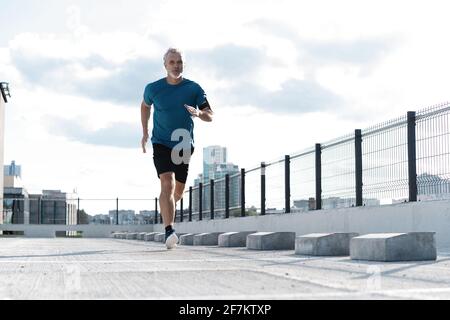 Fitness, Workout, Sport, Lifestyle-Konzept. Mann mittleren Alters, der in der Stadt läuft Stockfoto