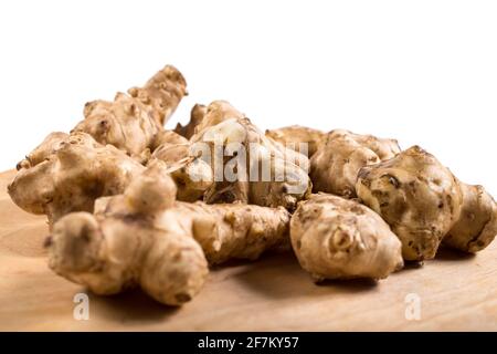 Knollen von Jerusalemer Artischocken aus der Nähe auf einem Holztisch auf weißem Hintergrund. Stockfoto