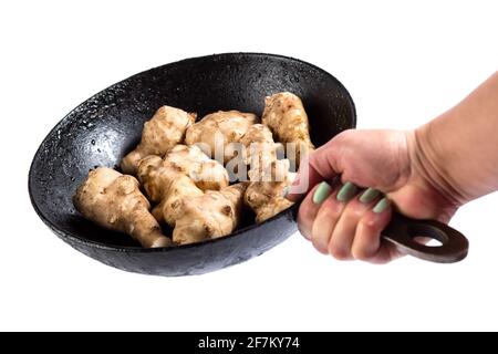 Frische Knollen von Jerusalemer Artischocken auf einer Bratpfanne aus nächster Nähe, isoliert auf einem weißen. Stockfoto