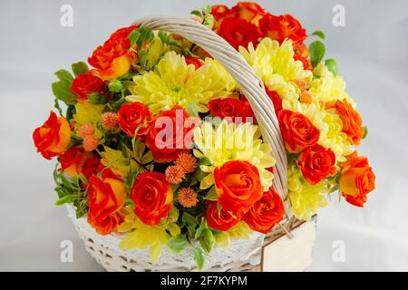 Blumenstrauß Weidenkorb, mit roten Rosen und gelben Chrysanthemen in Geschenkbox. Nahaufnahme, weißer Hintergrund Stockfoto