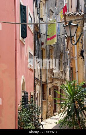 Altstadt von Korfu: Eine der engen, verwinkelten Gassen mit Waschanlagen, die an den dicht gedrängten Häusern und Wohnungen hängen Stockfoto