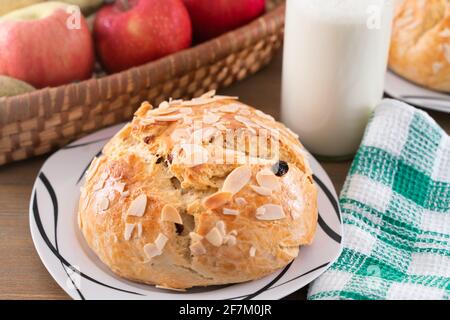 Frisch gebackener, hausgemachter Süßkuchen mit Mandeln und Rosinen auf Holztisch. Osterkaib. Korb mit Birnen und Äpfeln. Vintage Flasche Milch. Grün Stockfoto