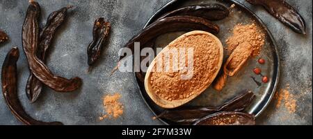 Trockene Johannisbrotkapseln und Puder Draufsicht Stockfoto