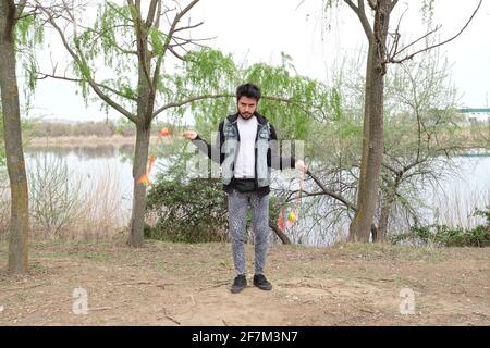 Junger Punk-Mann jongliert in einem Park mit Kariocas. Rock and Roll Lifestyle. Stockfoto