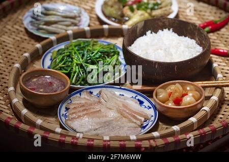 Vietnamesisches Familienmittagessen mit gekochten Schweinefleischscheiben Shrimp Paste Sauce und Beilagen Stockfoto