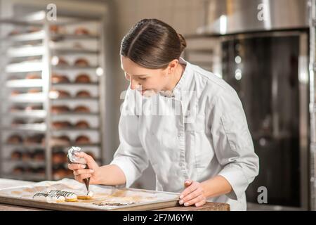 Frau mit Tüte über einem Kuchenblech Stockfoto