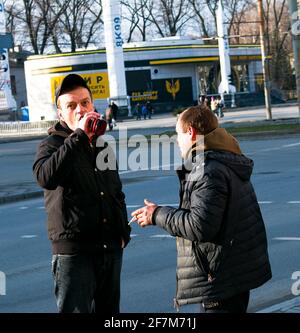 Dnepropetrovsk, Ukraine - 03.21.2021: Ein Mann trinkt Alkohol aus einer Flasche auf der Straße. Zwei obdachlose Männer fanden eine Flasche mit den Überresten von Alkohol i Stockfoto