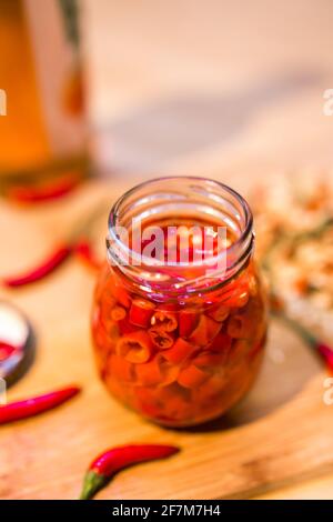 Rote Chilischoten mit Essig im Glasgefäß einpickeln Stockfoto