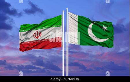 Pakistan und Iran Flagge im Wind gegen Weiße bewölkt blauer Himmel zusammen. Diplomatie Konzept, internationale Beziehungen. Stockfoto