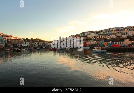 Der Hafen von Brixham fängt die Abendsonne ein, wie man sie in den Fenstern der Gebäude mit Blick auf den Hafen sieht. Stockfoto