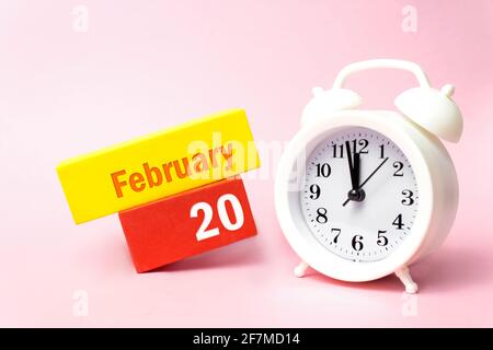 Februar. Tag 20 des Monats, Kalenderdatum. Weißer Wecker auf pastellrosa Hintergrund. Winter Monat, Tag des Jahres Konzept Stockfoto