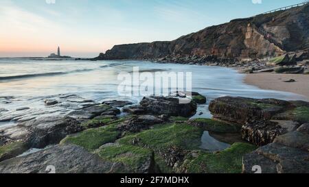 Blick von Old Hartley Bay, Northumberland, England, Großbritannien, mit Blick auf den St. Marys Leuchtturm, Whitley Bay und das offene Meer bei Sonnenaufgang. Stockfoto