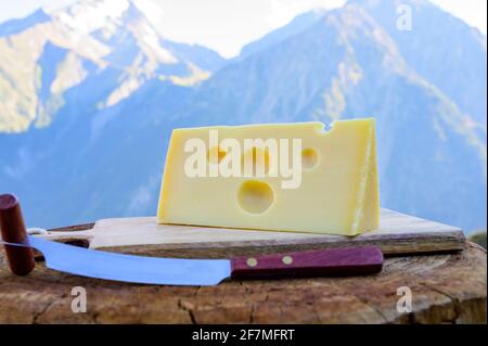 Käsesammlung, französischer emmental de savoie Käse mit runden Löchern, serviert im Freien in der Savoyer Region, mit Berggipfeln im Sommer auf dem Backgrou Stockfoto