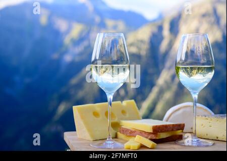 Schmackhafter Käse und Wein aus Savoyen in Frankreich, beaufort, abondance, emmental, Tomme und Reblochon de savoie Käse und ein Glas Weißwein serviert Stockfoto