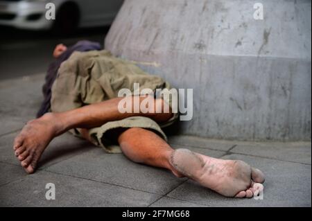 Obdachloser Mann, der auf dem Bürgersteig schläft Stockfoto