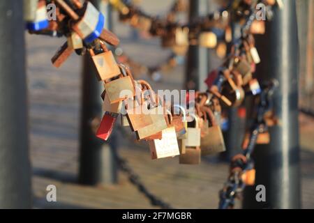 Eine Fülle von Vorhängeschlössern an einer Kette zwischen Pollern, was bedeutet Die Liebe zu einer anderen Person Stockfoto