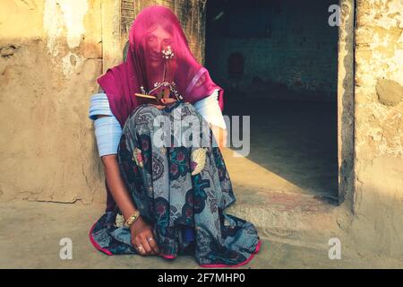 Jaisalmer, Indien - 19. Januar 2020 : Indische Rajasthani Frau in traditionellen bunten Kleidung und Schmuck sitzen vor ihrem Haus Stockfoto