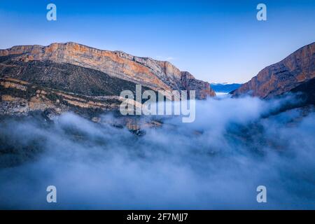 Die Schlucht Congost de Mont-rebei und die Einsiedelei Santa Quiteria bei einem nebligen Sonnenaufgang im Winter (Montfalcón, Aragon, Spanien, Pyrenäen) Stockfoto