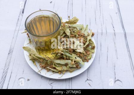 Eine Tasse Lindentee mit Blättern um ihn herum - linden Tee Vorteile Konzept Stockfoto