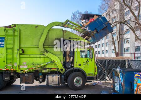 Recycelbarer Müllabfuhr-LKW und Service in der Stadt Toronto. Ein Fahrzeug der Marke GFL hebt einen großen Metallcontainer aus einem Apartmentgebäude Stockfoto