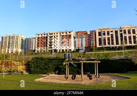 Gummireifen Schaukeln hing an einem Holzrahmen und Metallrohrrutschen mit natürlichem Sandboden Morgen Sonne Santander Cantabria Spanien Stockfoto