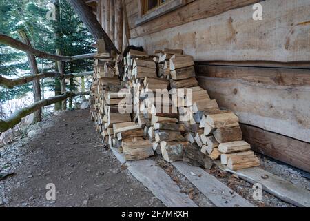 Haufen kleiner Holzstämme vor einem Häuschen. Stockfoto