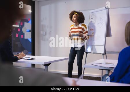 Gemischte Rasse Geschäftsfrau stehen an Whiteboard geben Präsentation zu verschiedenen Gruppe von Kollegen Stockfoto