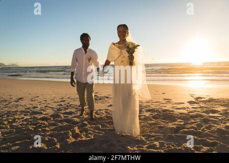 afroamerikanisches Paar verliebt sich zu heiraten, am Strand mit Händen zu gehen Stockfoto