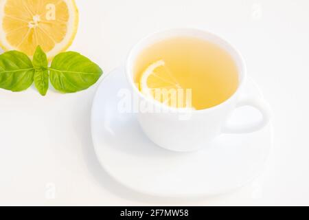 Tasse grüner Tee mit Zitronenscheibe, Basilikum und Minze isoliert auf weißem Hintergrund Stockfoto