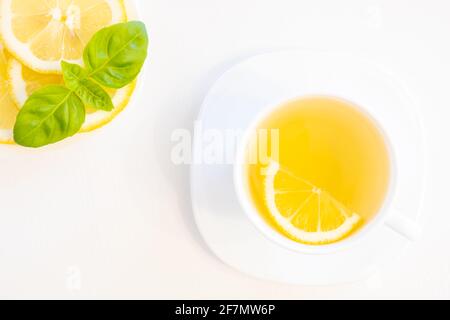 Tasse grüner Tee mit Zitrone, Basilikum und Minze schießen von oben isoliert auf weißem Hintergrund mit Platz für Text Stockfoto