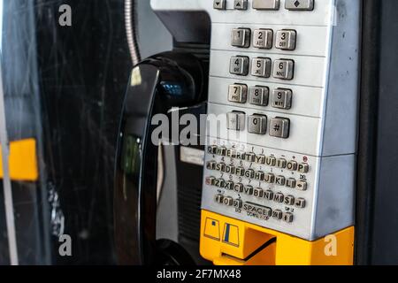 Ein altes verprügeltes Telefon in einem Einkaufszentrum im Südwesten von Ontario, Kanada. Schwarzer Empfänger, gelber Softfokus-Steckplatz für Kreditkarten. Silbernes Tastenfeld. Stockfoto