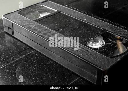 Ein veraltetes Videoband, das die Dämmerung auf einem alten schwarzen VCR-Player sammelt. Leeres Etikett, leere Kassette, Ontario, Kanada. Winkelansicht. Stockfoto