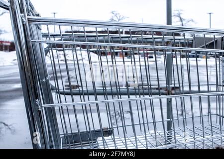 Ein silberner Einkaufswagen auf einem kargen Parkplatz mitten im Winter in London, Ontario, Kanada an einem trüben und bewölkten Tag. Stockfoto