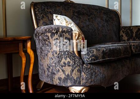 Angewinkeltes Foto eines französischen Loungesitzes im Renaissance-Stil mit schwarzem Spitzenmuster und goldenen Beinen in Ontario, Kanada, Februar 2021. Stockfoto