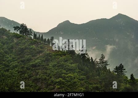 Drei-Schluchten-Staudamm, China - 6. Mai 2010: Nahaufnahme von Geen-Hügeln unter nebligen Morgenhimmel über dem Staudamm. Stockfoto