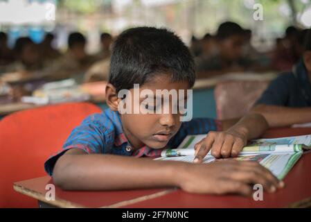 Varanasi, Indien. 10-14-2019. Ein Junge liest sein Lehrbuch in einem Internat, während er seine Hausaufgaben macht. Stockfoto