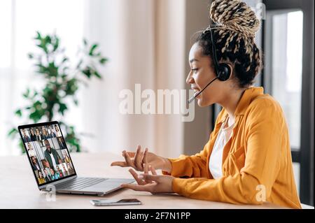 Brainstorming der Online-Business Group per Videokonferenz. Zufriedene afroamerikanische junge Frau, kommuniziert mit Geschäftspartnern per Videoanruf nutzt Laptop, multirassische Kollegen auf einem Laptop-Bildschirm Stockfoto