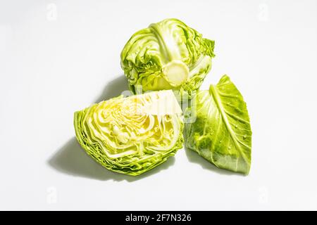 Frischer Jungkohl, halb und ganz isoliert auf weißem Hintergrund. Moderner, harter, dunkler Schatten. Gemüse zum Schneiden von Frühlingssalat. Veganes Essen, sterben Stockfoto