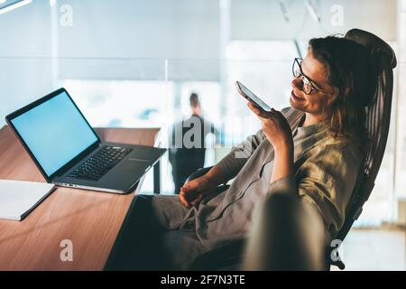 Junge Geschäftsfrau, die im Büro Audio-Nachrichten aufzeichnet Stockfoto