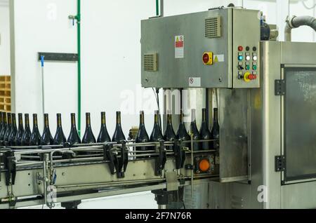 Weinproduktionsmaschine, die die Flaschen füllt. Industrieproduktion. Stockfoto